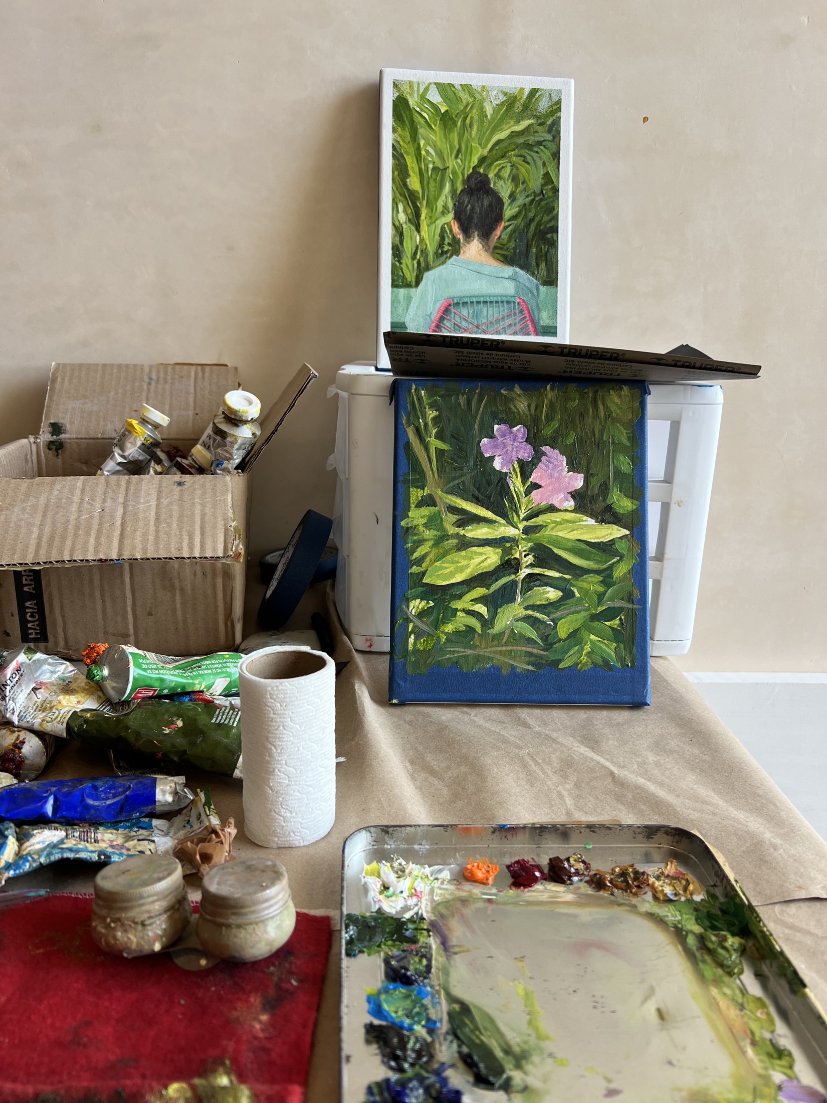 Mesa de estudio con pinturas de plantas, tubos y una paleta