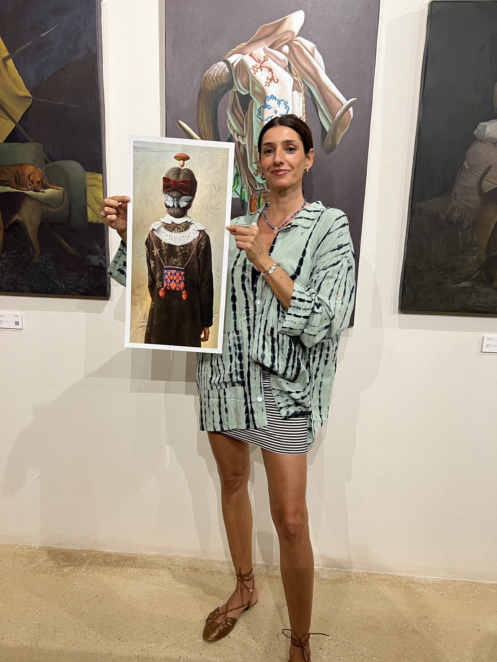 Artista sonriente sostiene su obra en una exposición
